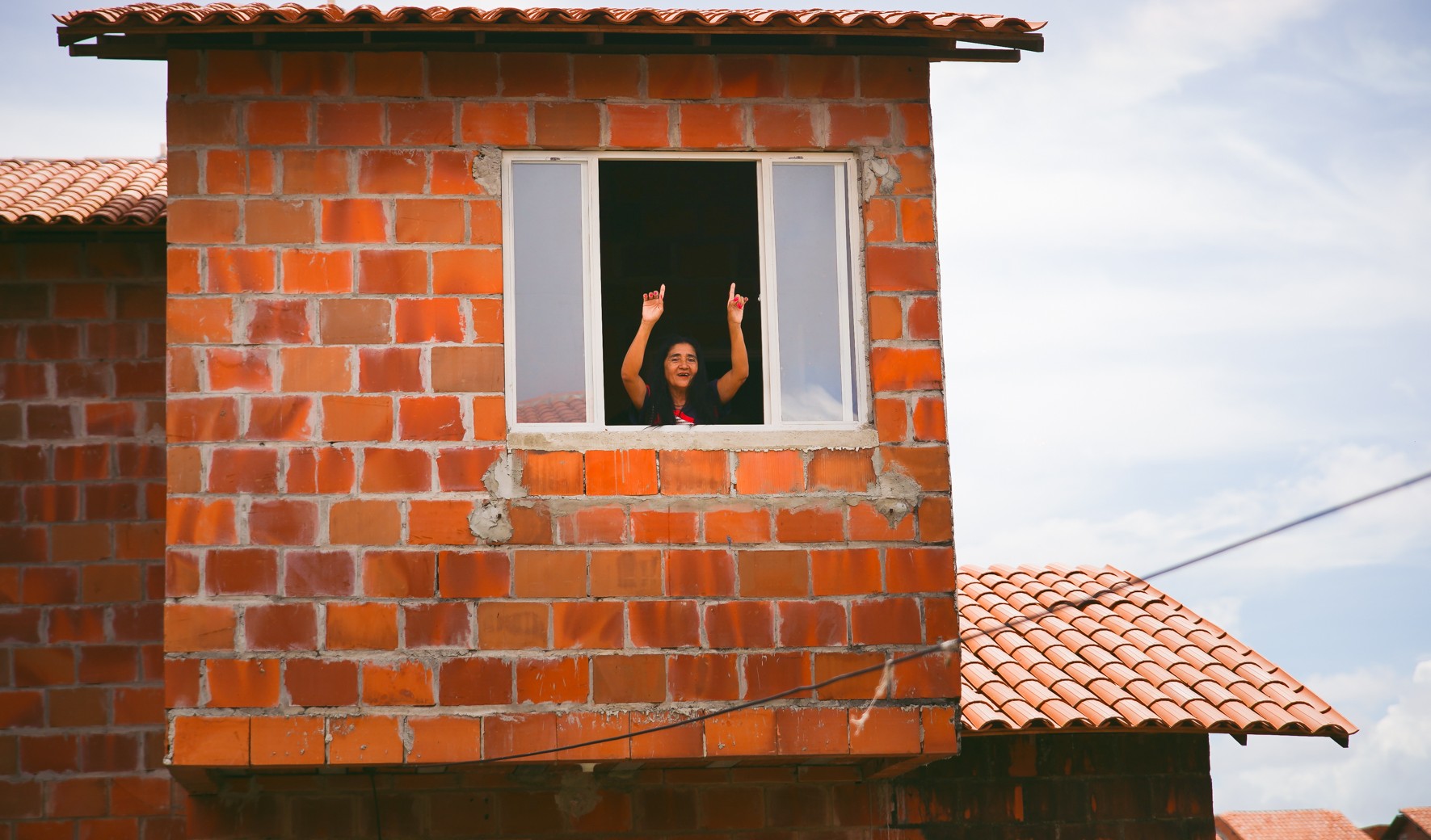 mulher acena da janela de uma casa